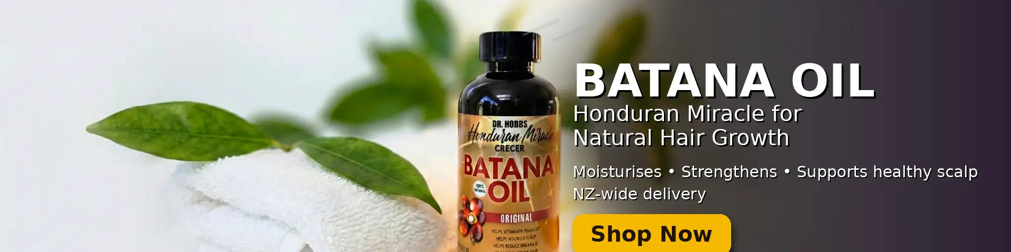 A dark amber glass bottle of batana oil with a black cap and label featuring red, gold, and white text.